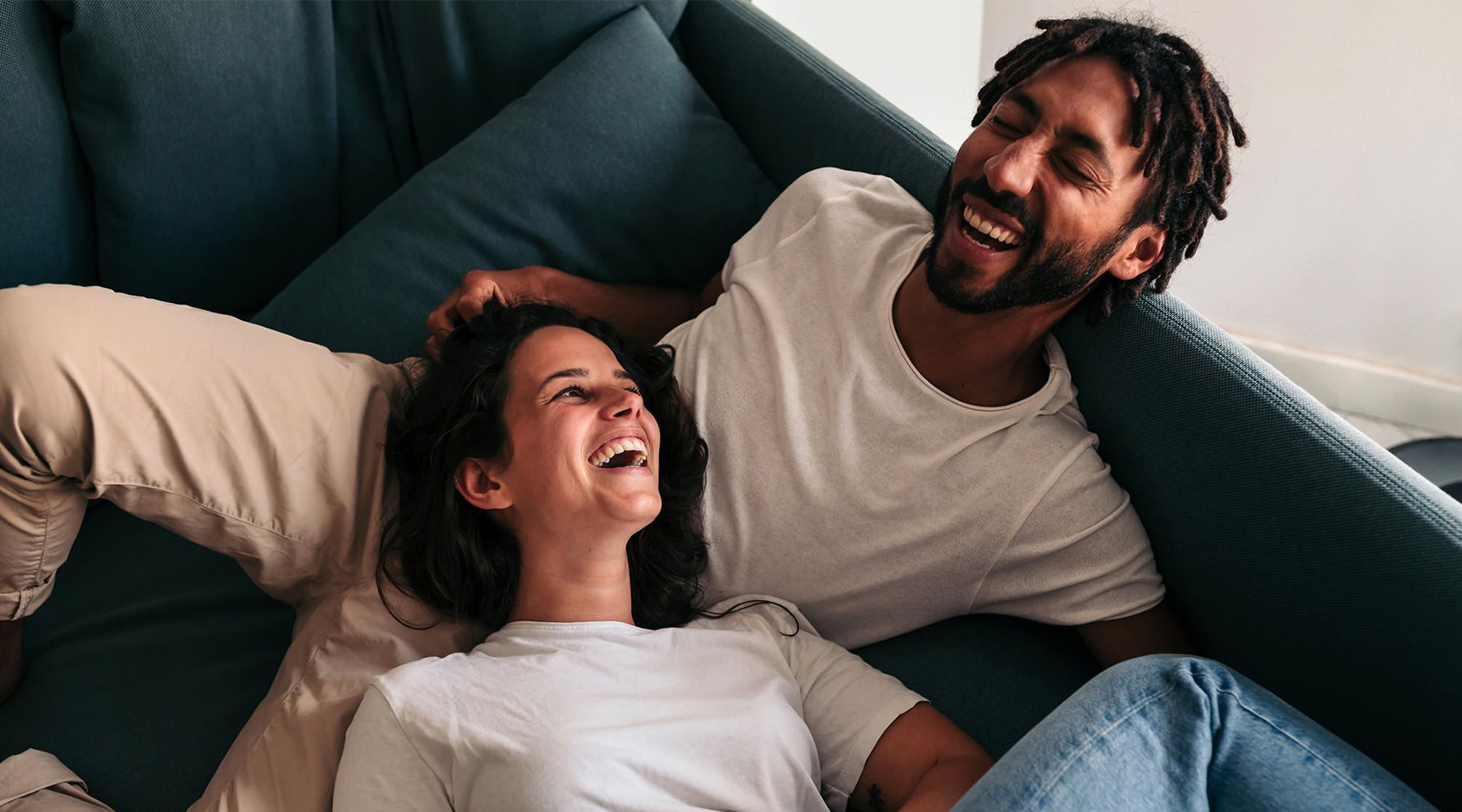 a man and a woman laughing while lying on a couch